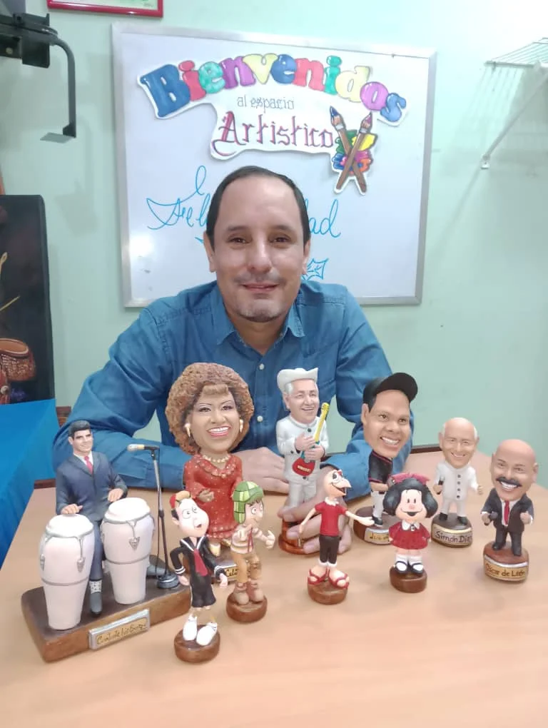 José Rueda, escultor artesanal, posando con su colección de figuras y cabezones personalizados de personalidades y artistas.